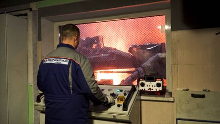 Back view of a worker in uniform standing in the control room of the steel making workshop. Stock...