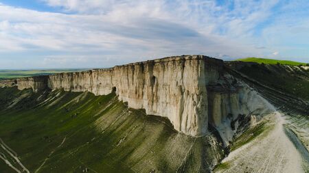 Top view of beautiful white rock with green grass on background of blue sky. Shot. Panorama of white...