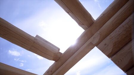 Close-up view of wooden structure of house. Clip. Building house of good wooden logs. Construction of wooden house on blue skyの写真素材