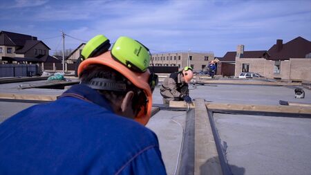 Workers make measurements measuring tape on construction. Clip. Builders in uniform and hard hat...