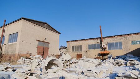 Lot of trash in abandoned factory. Stock footage. Pile of white trash on back of abandoned plant on blue sky background. Not eco-friendly method of getting rid of garbage in factoryの写真素材