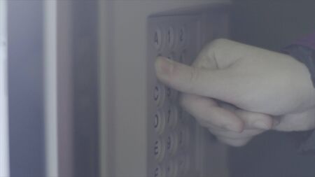 Woman presses buttons on vending machine. Stock footage. Female hand enters code on panel of vending machine. Keypad with numbers and letters from vending machineの写真素材