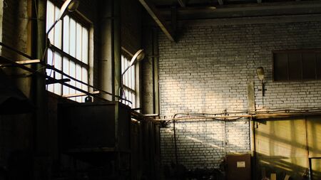 Old abandoned warehouse of industrial enterprise. Stock footage. Small abandoned room of old warehouse cluttered and illuminated by sun rays making their way out of windowsの写真素材
