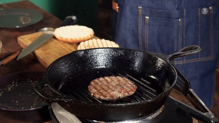 A hamburger patty frying on a cast iron grill. Stock footage. Hamburger Patty is prepared on the grill panの写真素材