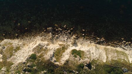 Aerial view of sea waves and fantastic Rocky coast. Shot. Top view of the rocky cliff by the sea