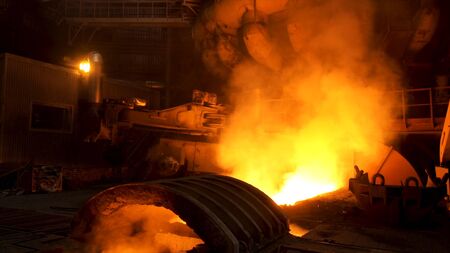 Close up for the electric furnace with melting metal and rising smoke. Metallurgical factory, release of steel in the foundry, heavy metallurgy concept.の写真素材