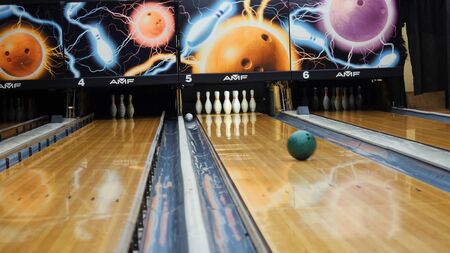 View of colorful ball hitting the bowling pins on bowling alley in a sport club. The bowling balls return machine system conceptの写真素材