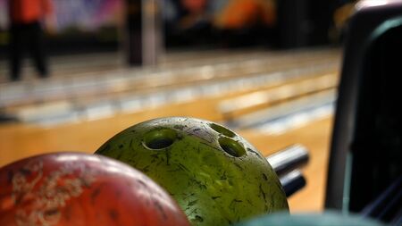Close-up view of bowling player hand taking colorful ball from bowl lift. People playing bowling -...