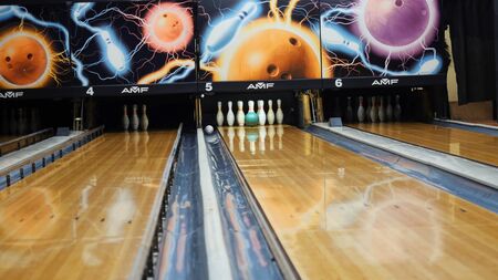 View of colorful ball hitting the bowling pins on bowling alley in a sport club. The bowling balls return machine system conceptの写真素材