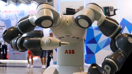 Industrial robotic machine at the industrial international exhibition, science concept. Close up for a robot moving his arms with people moving on the background.の写真素材