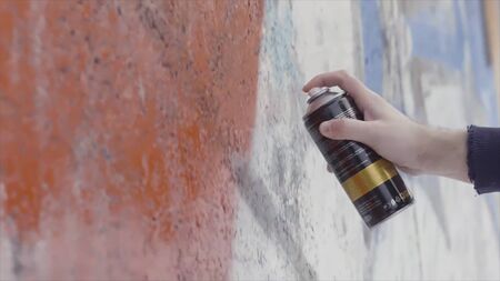 Close up of artist drawing and spraying paint on the wall, street art concept. Side view of a man hands during the process of creating graffiti on a concrete wall.の写真素材