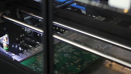 Close up for the robotic mechanism soldering the chip at the computer factory, technology and...