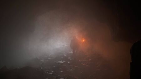 Traveler with torch in dark cave. Stock footage. Man with torch is selected from dark misty cave....