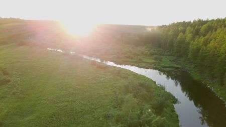Bright sunny rays falling on green forest by river. Stock footage. Warm sunlight falls on beautiful...