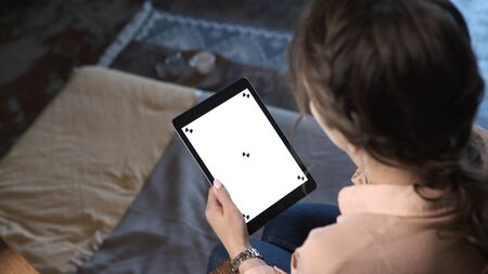 Close-up of young pretty woman with brown hair holding iPad, typing and sliding at the chroma key...