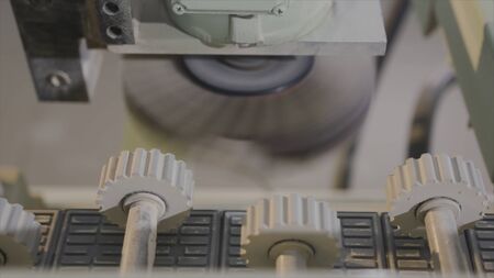 Close-up rotating parts with gears of industrial equipment. Action. Inside modern woodworking machine with moving gears. Wooden gears move forward wooden boardsの写真素材