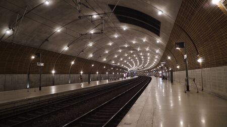 Underground subway tunnel with bright lighting. Action. Simple stone interior of underground metro with bright lighting on tracksの写真素材