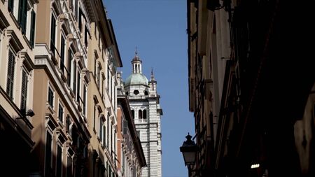 Part of Cathedral on background of houses. Action. Cathedral tower is visible from narrow street...