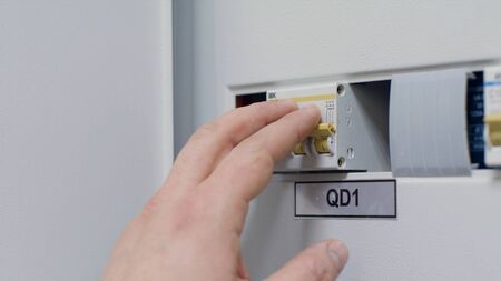 Close up of the man hand switching off and on automatic fuse, electric equipment concept. Male hand...