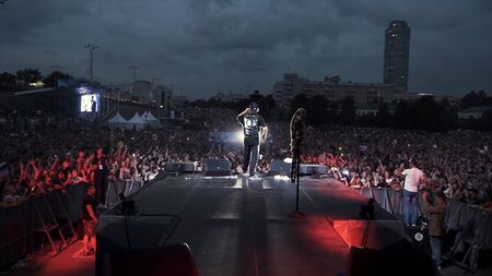 Russia - Yekaterinburg, 09.12.2019: Crowd of people gathered on square in front of stage before during the concert. Action. Rear view of a singer on the stage during his perfomance.のeditorial素材