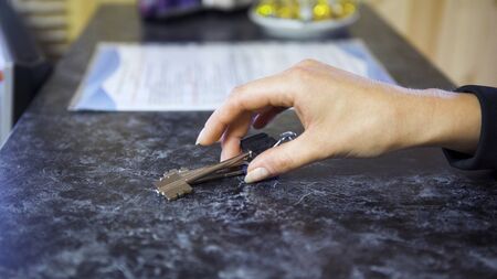Close up of a table and the process of passing keys by two women. Art. One hand putting keys on the...