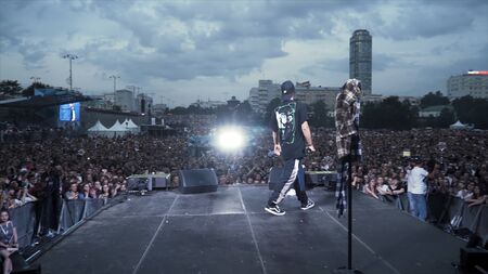 Russia - Moscow, 09.12.2019: Rap or Hip-Hop musician performing on stage in front of cheering crowd. Action. Rear view of an artist during the concert.のeditorial素材