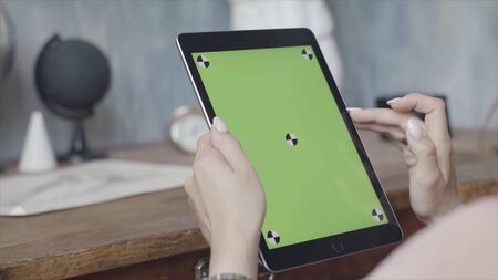 Side view of a woman holding tablet pc with green screen on wooden table background. Stock footage....