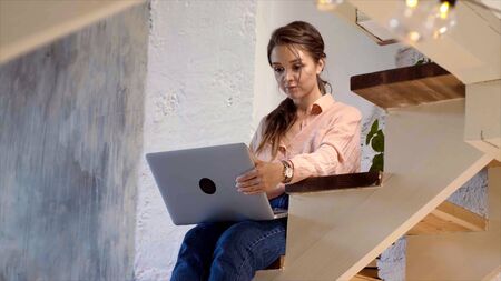 Girl using her laptop in her house. Stock footage. Young woman working at laptop at home