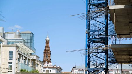 Side view of a new multi storey building under construction. Stock footage. The contrast between modern building and old beautiful church or temple.の写真素材