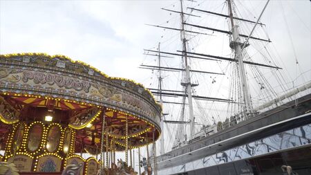 Beautiful carousel on background of large ship. Action. Bright carousel spinning on background of...