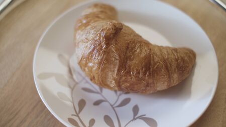 French croissants on a plate, close up. Delicious freshly baked crispy croissant lying on the plate on wooden table background.の写真素材