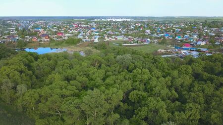 Panoramic aerial view of beautiful small town and surrounding area with meadows. Amazing green trees...