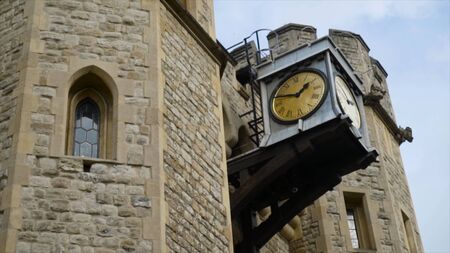 Close-up of old street clock on stone wall of building. Action. Street clock with roman numerals on...