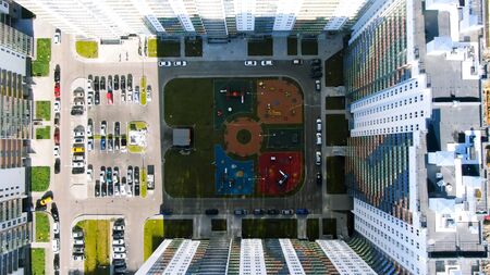 Aerial view of tall skyscrapers with colorful facades with parking space for cars and a children...