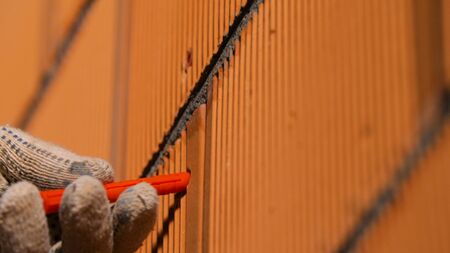 Carpenter inserts dowel. Stock footage. Close-up of man in gloves inserting dowel into hole in brick...