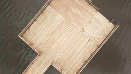 Top aerial view of water and wooden pier in a summer time. Camera moving away from the wooden pier...