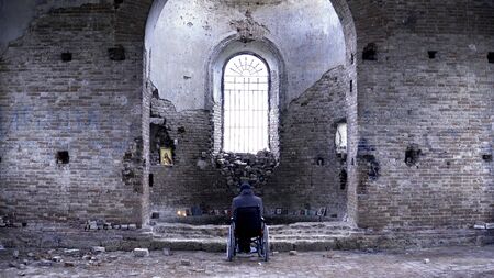 Man in a wheelchair in a ruined Church. Footage. Back view of a man in an abandoned Church. The concept of memories.の写真素材