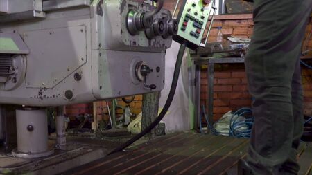 Close up of unrecognizable machine operator turning handle of machine while adjusting it. Side view...