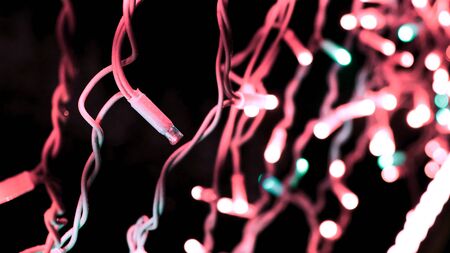 Christmas romantic lights of blinking garland on black background. Decorative garland in night...