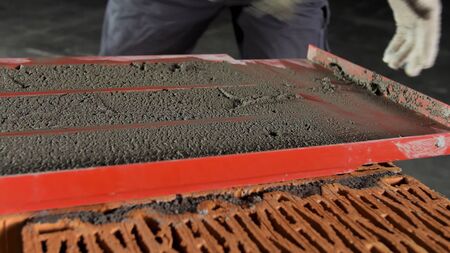 Close up of a bricklayer on a construction site with a trowel. Industrial worker using trowel for...