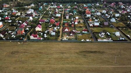 Aerial view o beautiful small cottages located by the forest and the green field, ecology concept. Stock footage. Flying above the village in a summertime.の写真素材