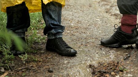 People trekking in the forest under the rain. Close up of male legs standing on the wet forest ground with falling rain drops.の写真素材