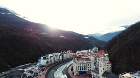 Photos of buildings, funicular, river at foot of mountains with the bright sunset on the background....