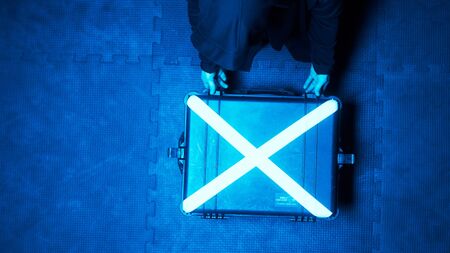 Boxer set. Stock footage. Suitcase with boxing gloves glows when opened. Man opens glowing suitcase with boxing gloves in dark room of sports hallの写真素材