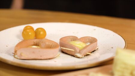 Close-up on plate of fried eggs with sausages in shape of hearts. Stock footage. Romantic Breakfast with heart-shaped eggs for your loved onesの写真素材