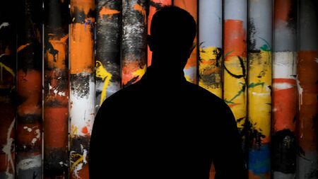Man looking at art painting in museum, rear view. Concept. Male silhouette looking at rotating tubes covered by colorful brush strokes in dark room.の写真素材