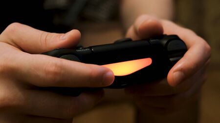 Male hands holding joystick, playing video games on console, having fun. Close up of man hands...