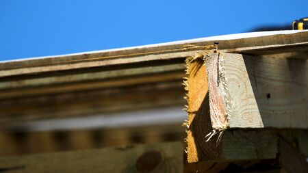 Close up of roofing wooden construction with a nail and a tight rope around it on blue sky...