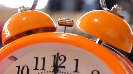 Close up of retro alarm clock going off on blurred background. Orange alarm clock details for waking...