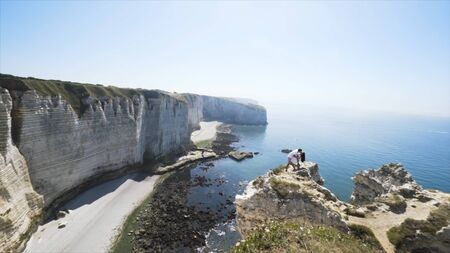 Couple hugging on the edge of the cliff on blue cloudy sky background. Love and travel, happy...